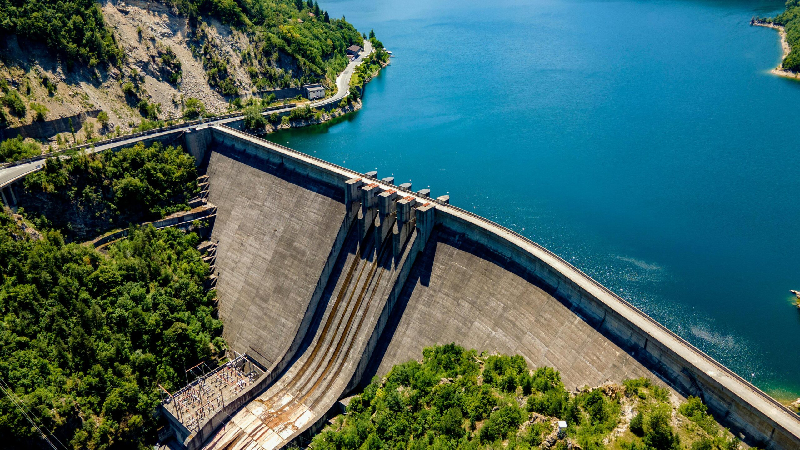 A stunning aerial view of Vacha Dam surrounded by lush greenery and blue waters in Bulgaria.